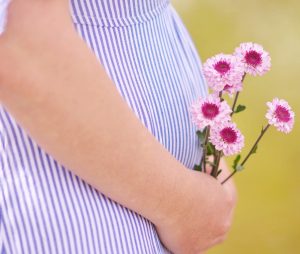 woman with baby bump holding flowers